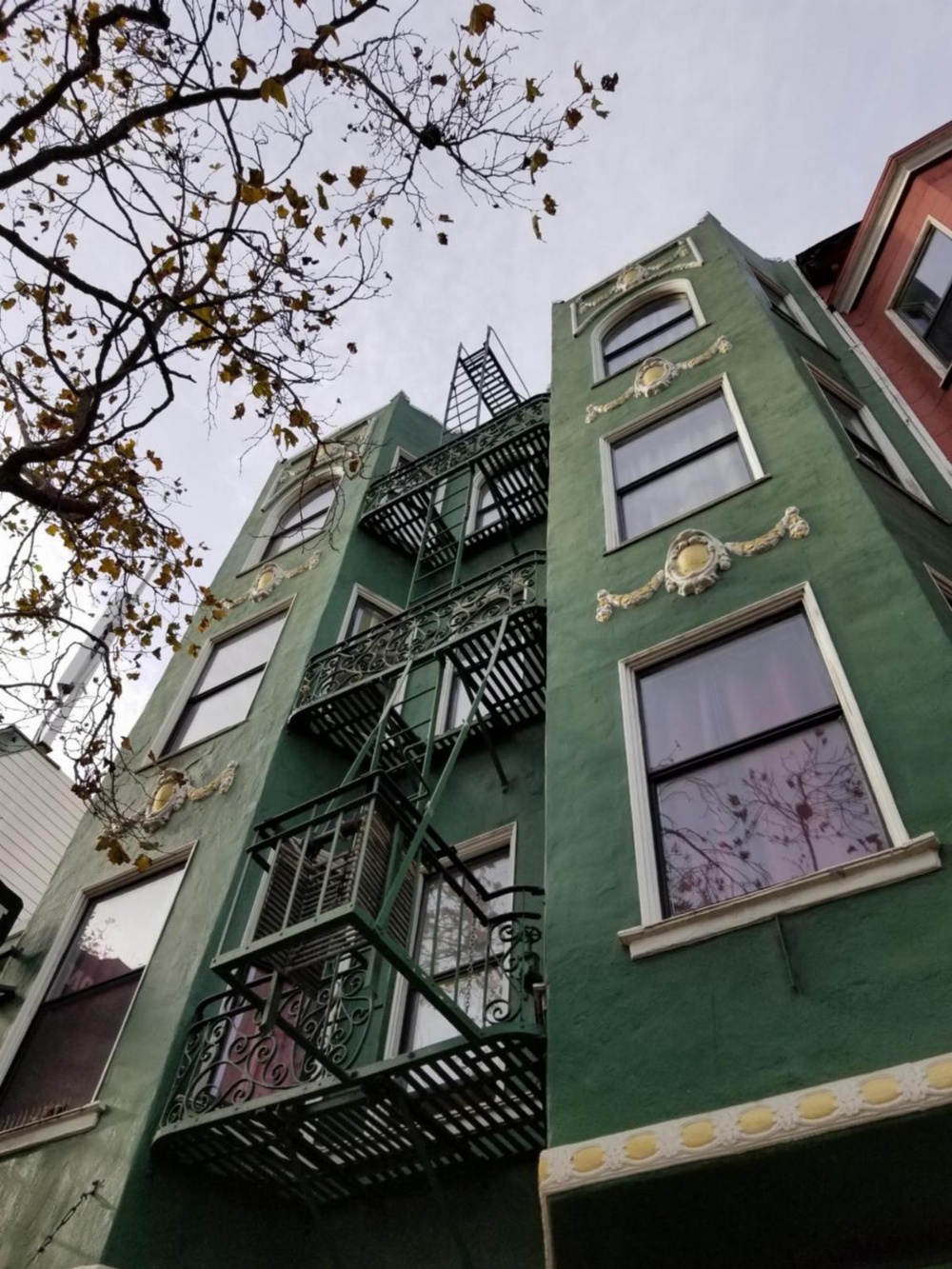 A green building with a fire escape and balconies